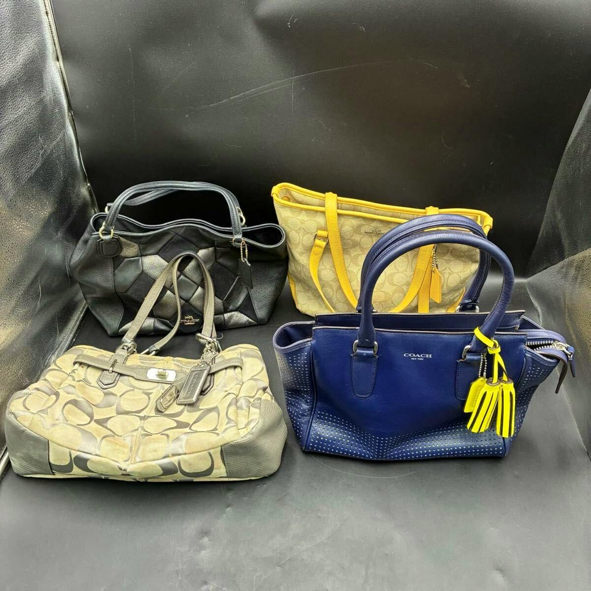 Four COACH handbags (black, yellow, beige patterned, and blue) arranged on a black backdrop.
