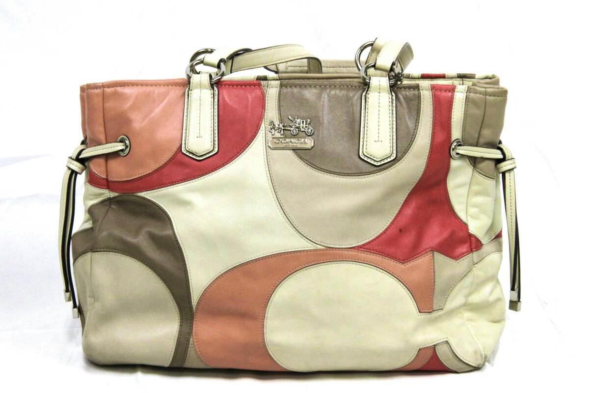 Front view of a pink and beige Coach canvas handbag with circular color-block panels and dual top handles.