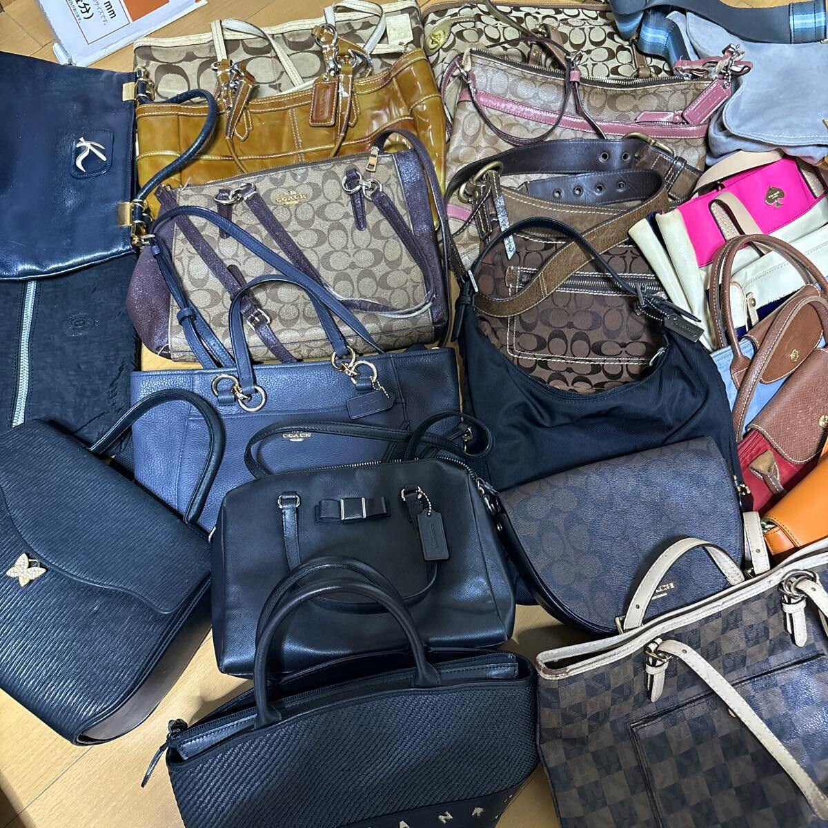 Top-down photo showing a large mixed set of Coach and other handbags and shoulder bags arranged together on the floor.