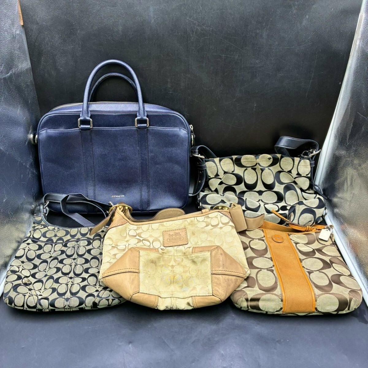 Five Coach handbags and shoulder bags arranged together against a dark backdrop showing different colors and signature patterns.