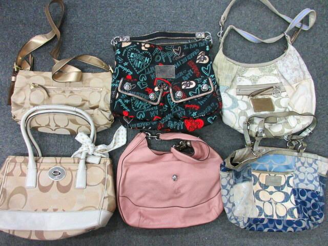 Six Coach handbags and shoulder bags arranged together on a gray floor, in various colors and patterns.