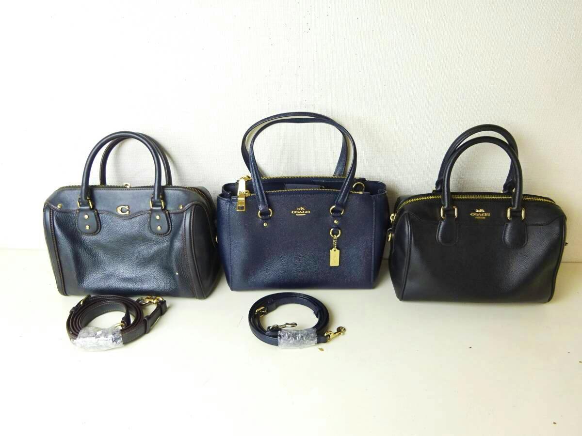 Three Coach handbags displayed side by side on a white surface with two detachable straps placed in front.