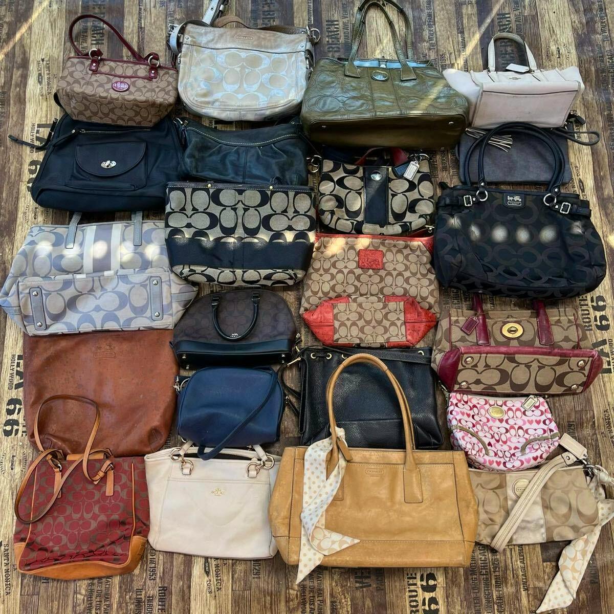 Top-down view of a large assortment of Coach handbags and totes arranged on a wooden floor.