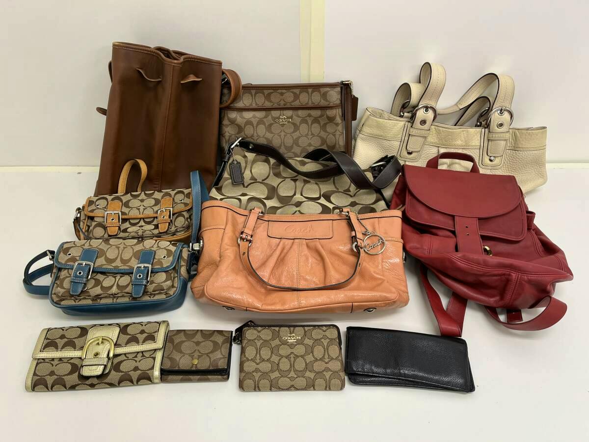 Several Coach handbags, shoulder bags, and wallets arranged on a white surface, showing a multi-piece lot.