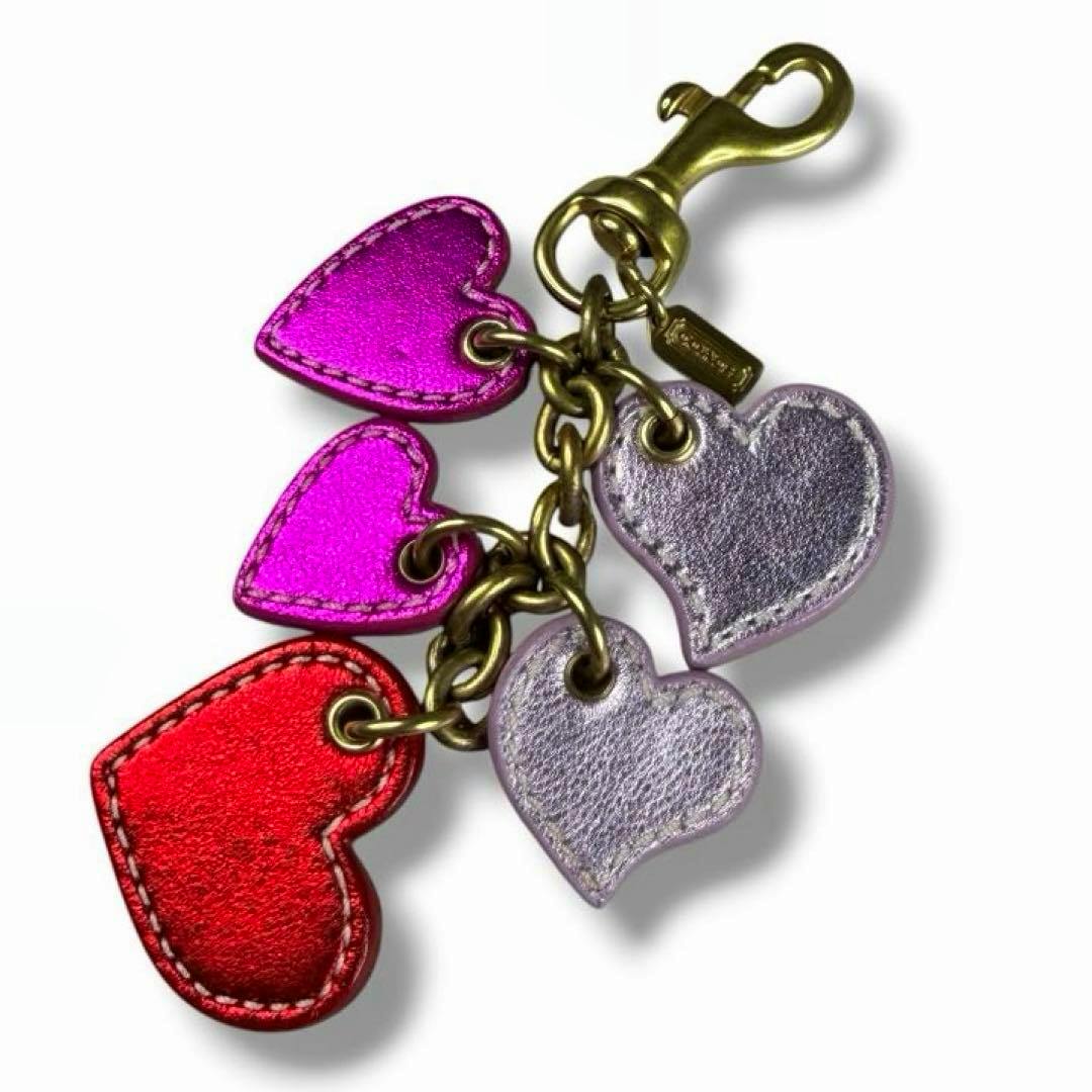 Close-up of the Coach heart charm leather keychain showing multiple metallic heart-shaped leather charms and brass hardware.