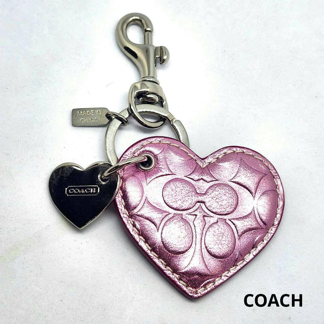 Pink heart leather Coach keychain with embossed signature pattern, attached metal heart charm, and a metal swivel clasp.