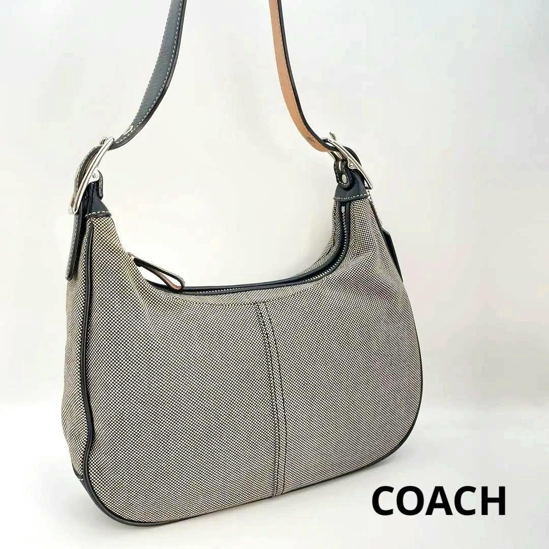 Gray COACH hobo one-shoulder canvas bag with black leather trim and single shoulder strap shown at an angled view.