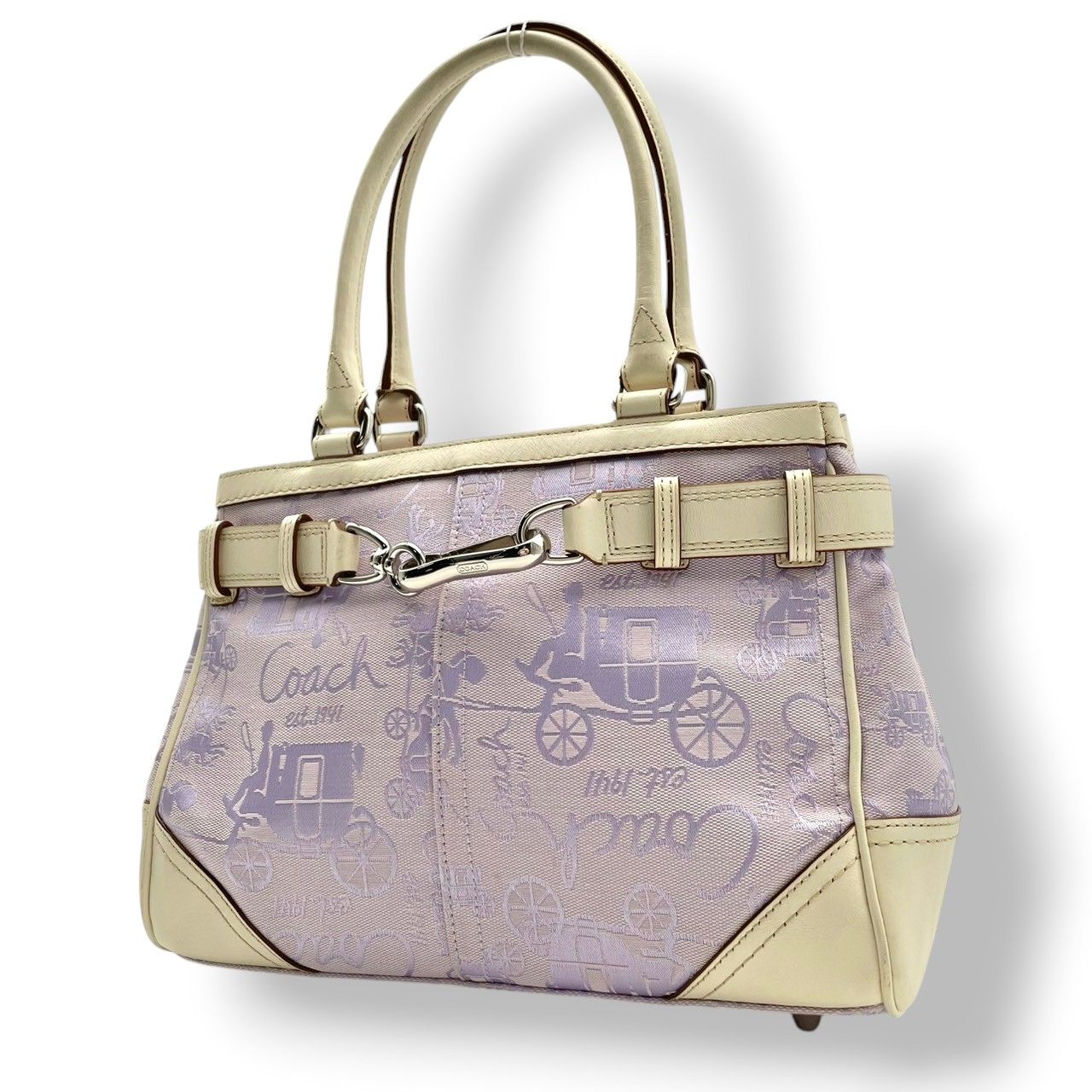 Light purple Coach canvas tote bag with horse-and-carriage pattern, ivory leather trim, and double top handles.