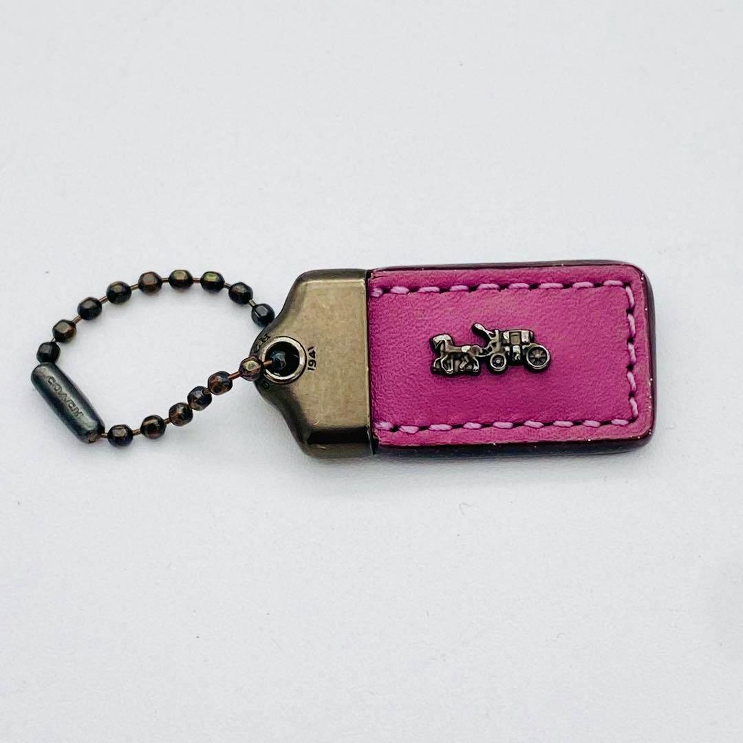 Purple Coach horse-and-carriage hangtag bag charm with metal hardware and ball-chain attachment.