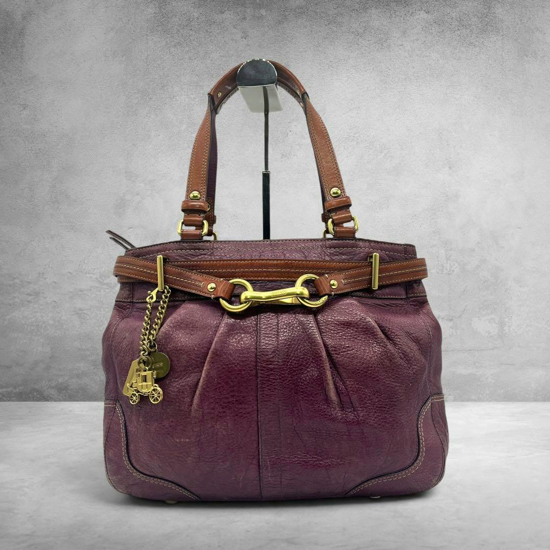 Purple COACH Horsebit leather tote bag with brown straps and gold hardware shown on a display stand.