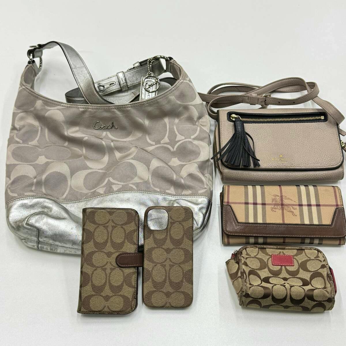 Several bags and small accessories (Coach and other brands) including a Coach canvas shoulder bag, a small crossbody, wallets, and two Coach-pattern iPhone cases on a white background.
