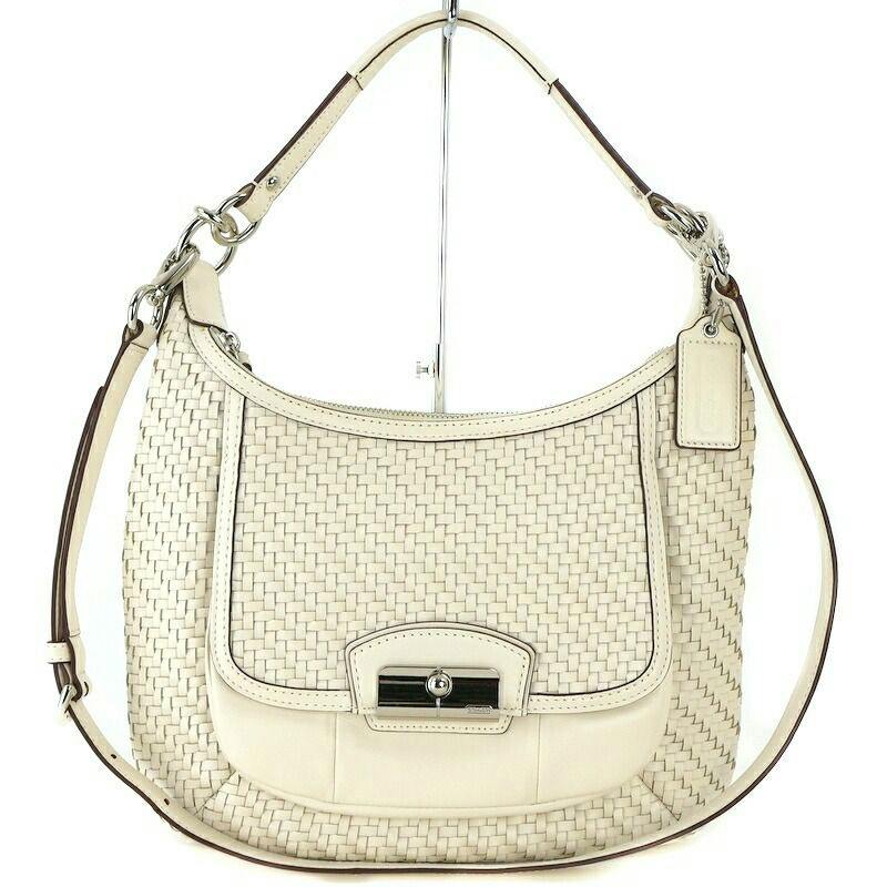White leather Coach Kristin woven shoulder bag shown front view with single strap and turn-lock closure.