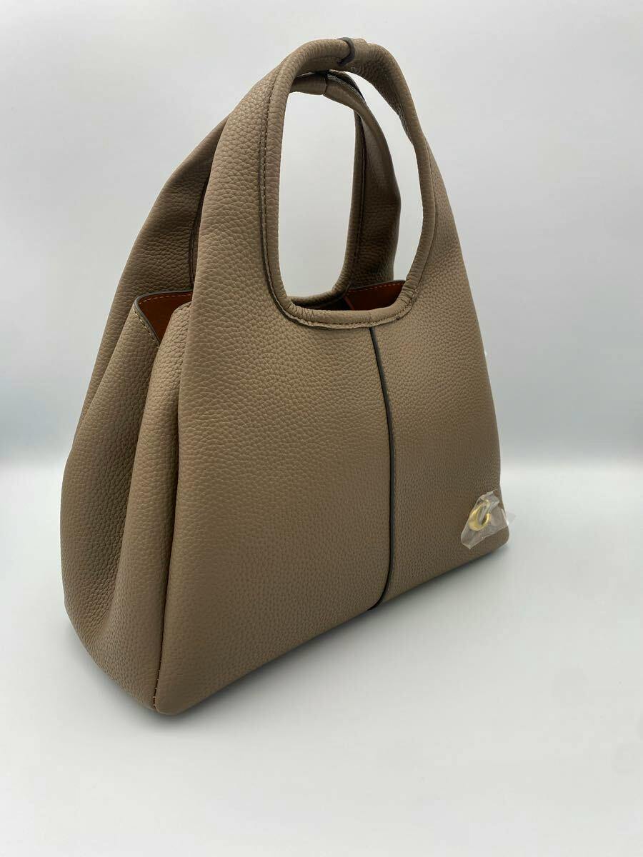 Dark stone COACH bag with top handles and pebbled exterior shown at a three-quarter side angle.