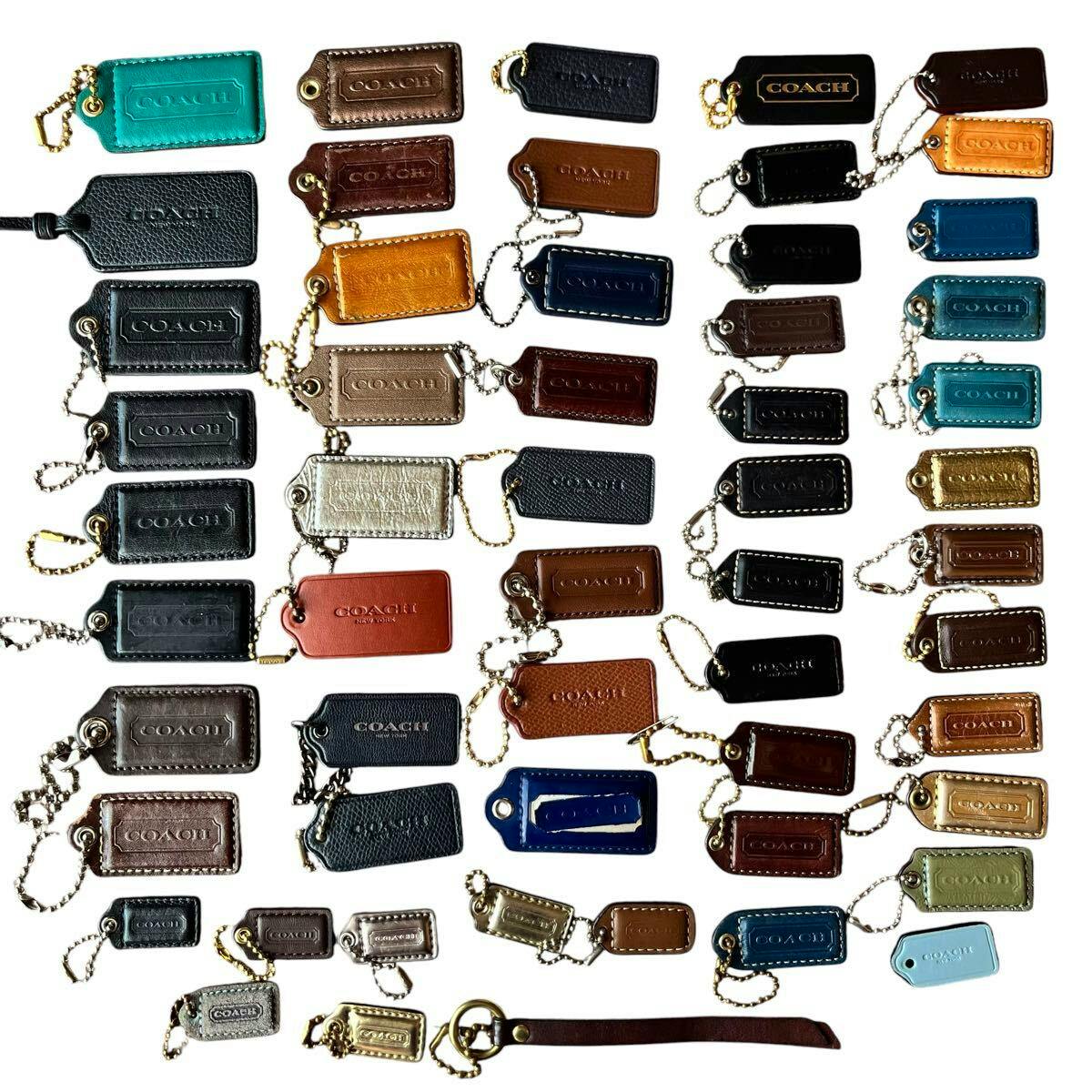Multiple COACH leather bag charms and hangtag keychains in various colors arranged on a white background.