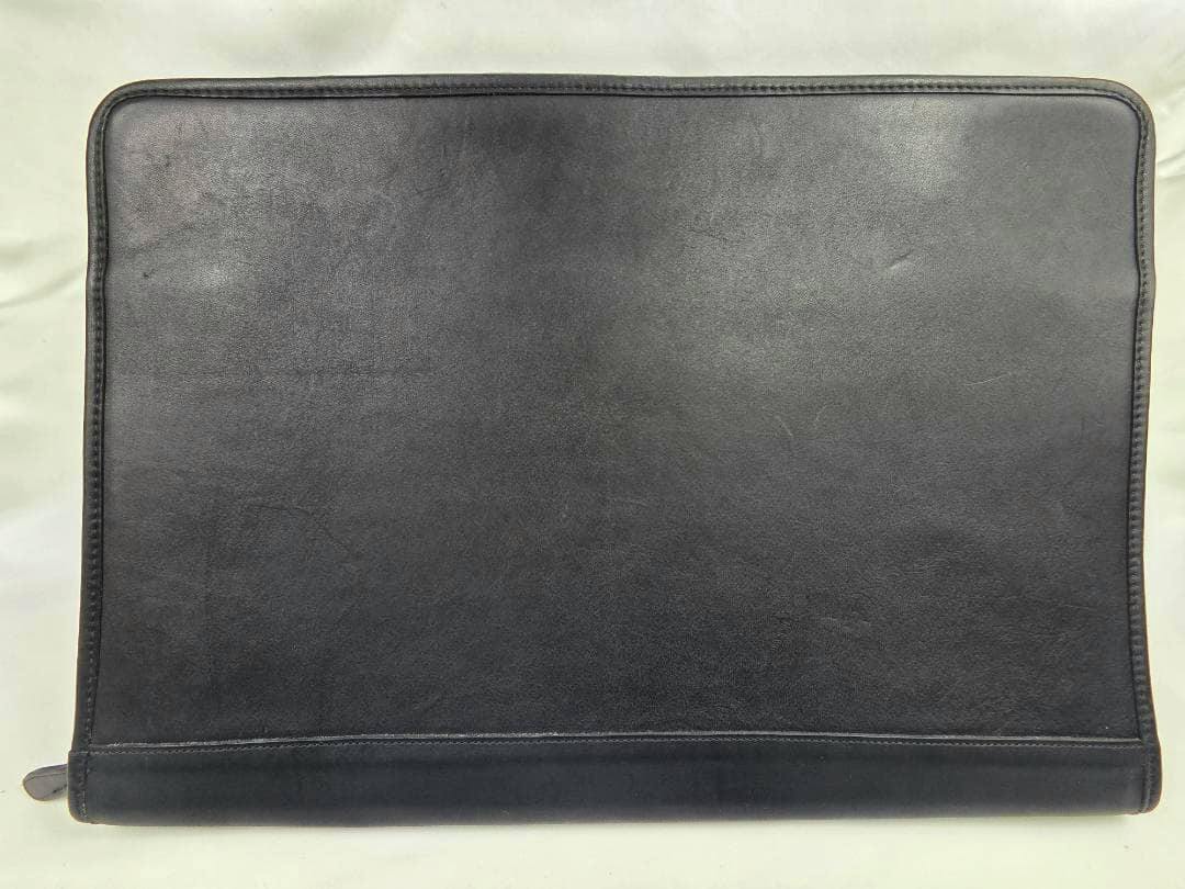 Black leather COACH clutch/document case laid flat showing the front exterior on a light background.