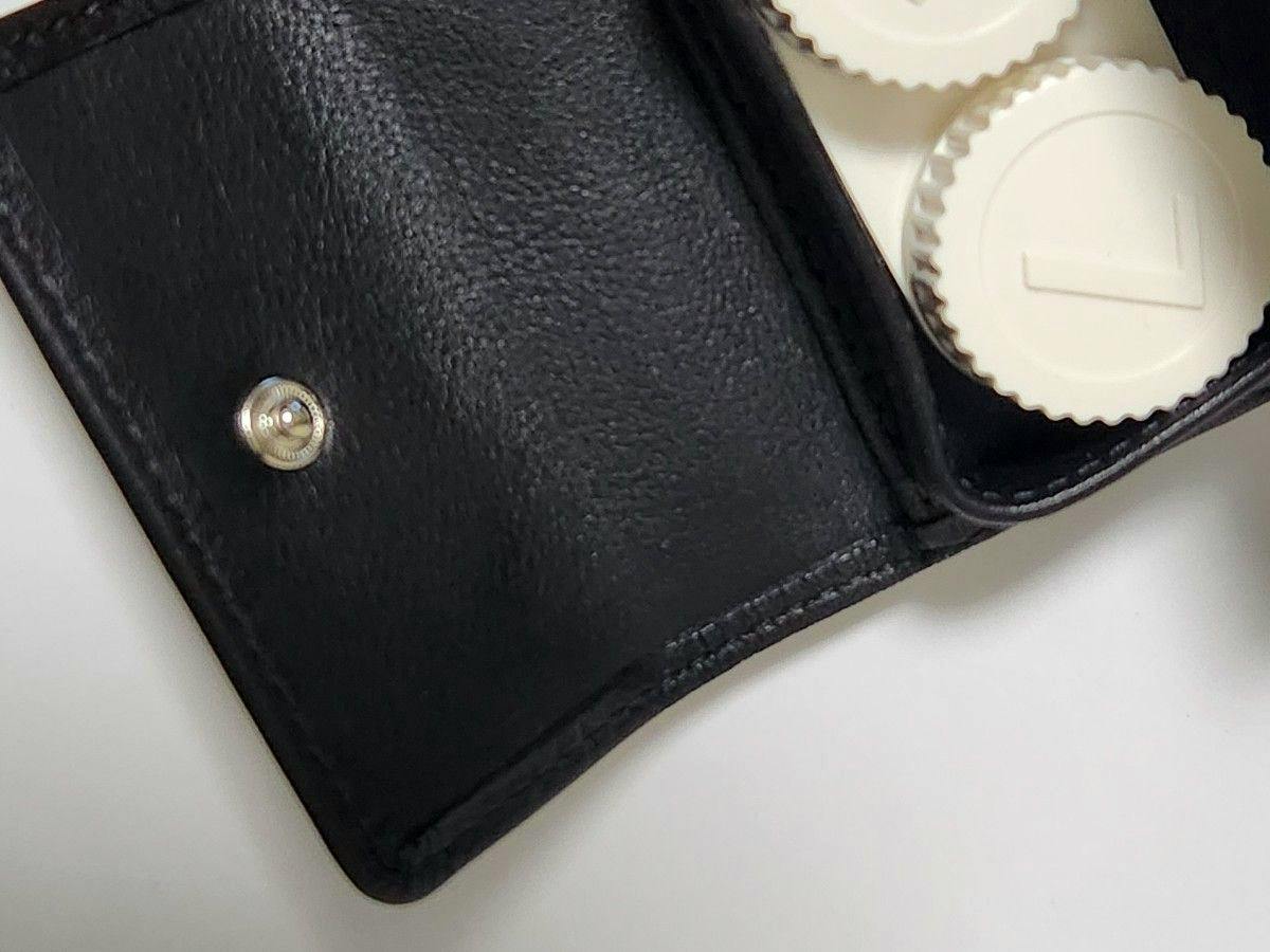 Black leather contact case opened showing the interior snap closure and two white contact lens containers.