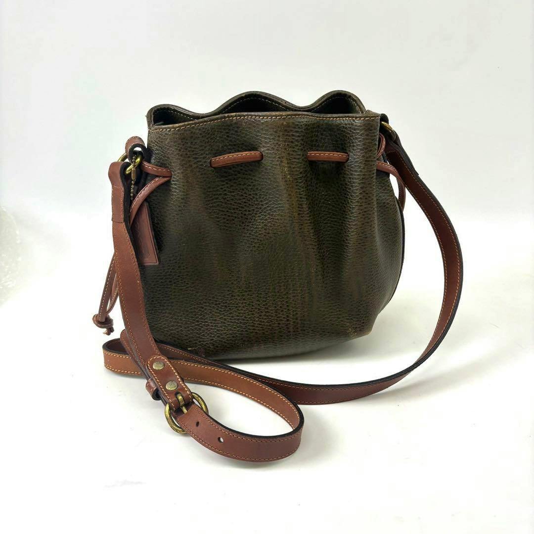 Brown COACH leather drawstring shoulder bag with contrasting brown strap shown on a white background.