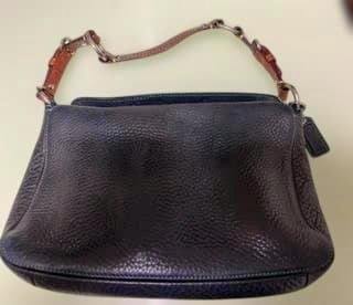 Black COACH leather handbag with a short leather-and-chain shoulder strap shown on a light surface.