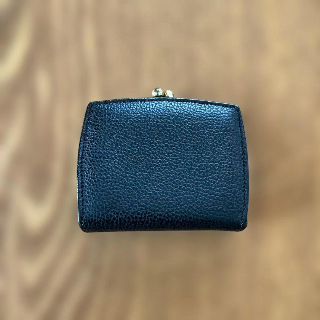 Black pebbled leather coin case with a metal kiss‑lock clasp photographed flat on a wooden surface.