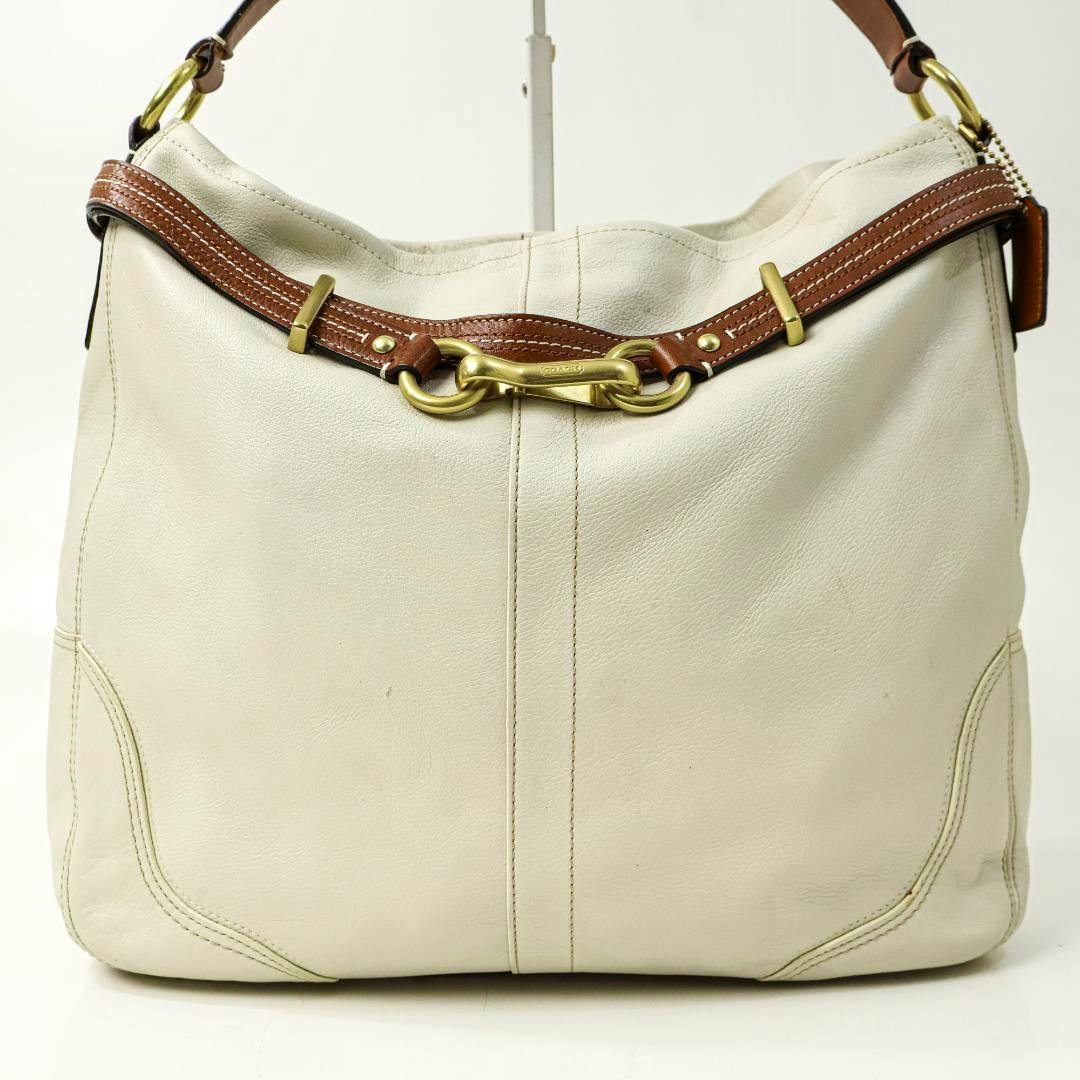 Front view of a white cow leather Coach one-shoulder bag with brown leather trim and gold-tone horsebit hardware.