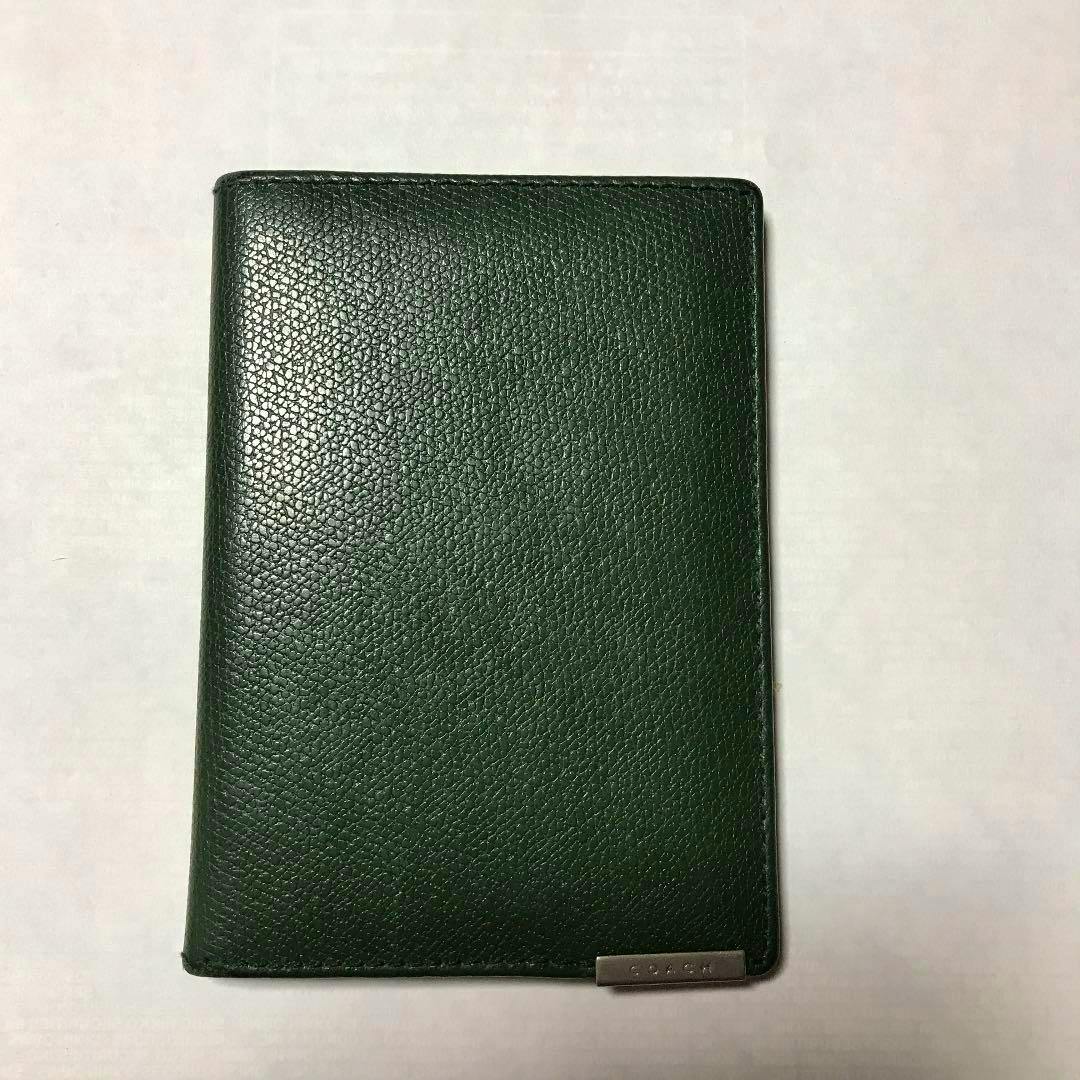 Closed green pebbled leather pass case shown from the front with a small metal Coach logo plate at the bottom right.