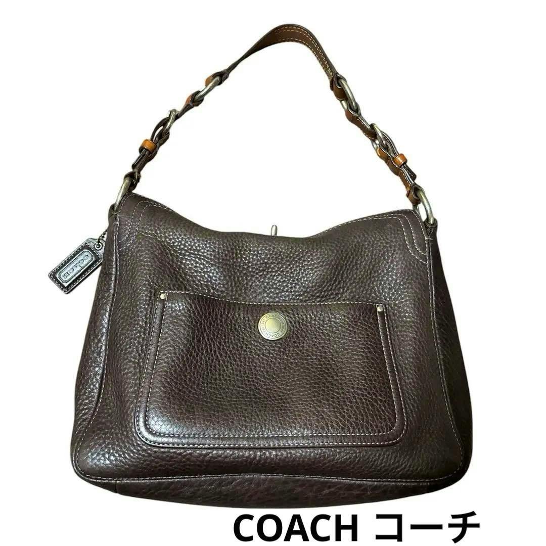 Front view of a brown leather COACH shoulder bag with a short chain-linked handle and a front pocket.