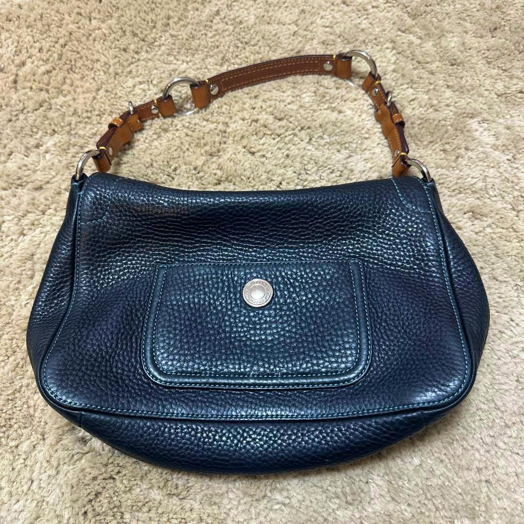 Black pebbled leather Coach shoulder bag with a brown leather strap and an exterior front pocket featuring a round metal snap.
