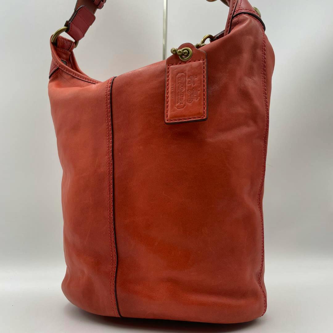 Red leather Coach shoulder bag shown from the front with strap and leather hang tag visible.