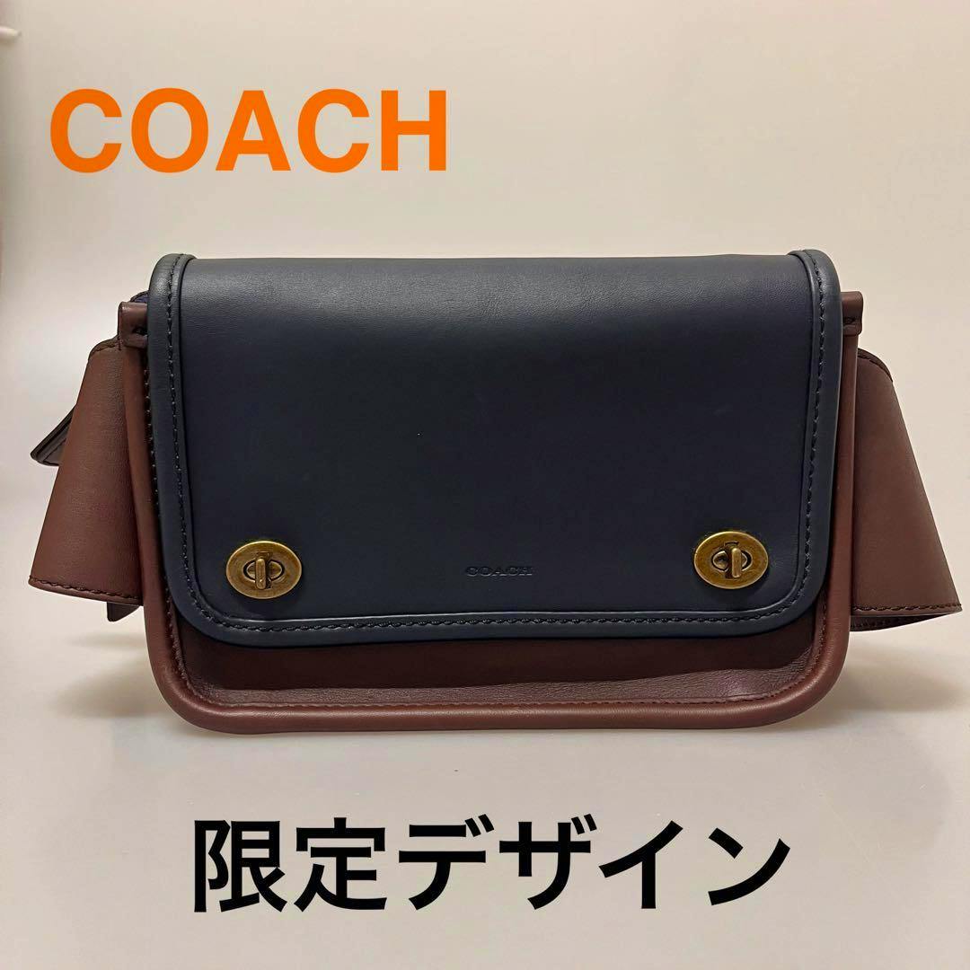 Front view of the COACH leather bicolor body bag showing the flap with two gold turn-locks.