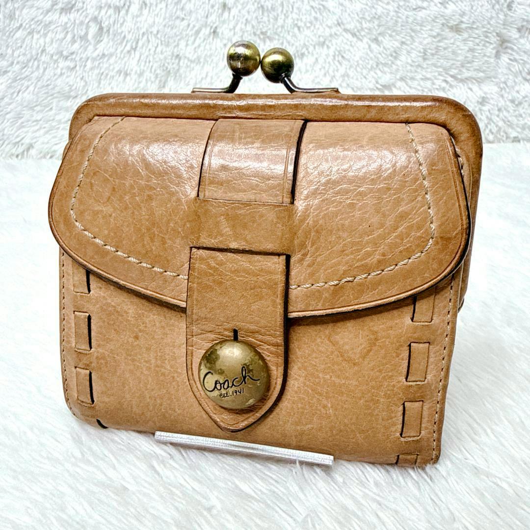 Front view of the COACH Legacy Kisslock leather wallet in tan showing the kisslock clasp and Coach-branded button.