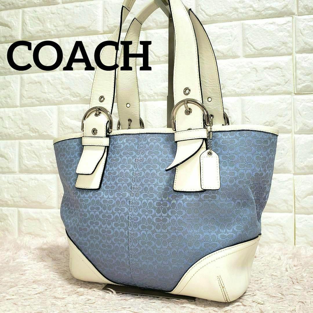 Light blue COACH mini signature canvas handbag tote with white leather trim and handles against a tiled background.