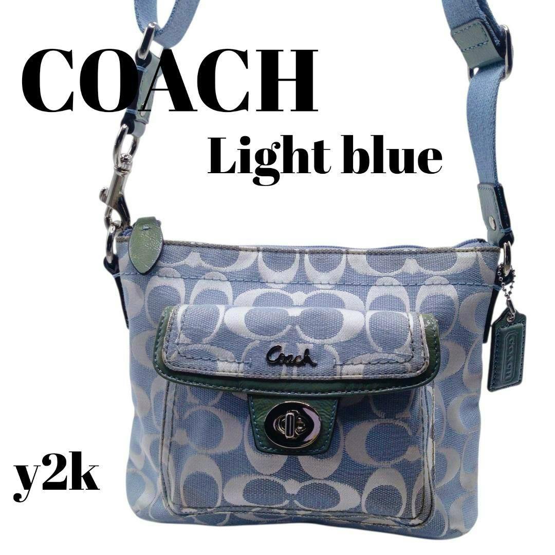 Light blue COACH signature canvas shoulder bag with front flap pocket and adjustable strap on a white background.