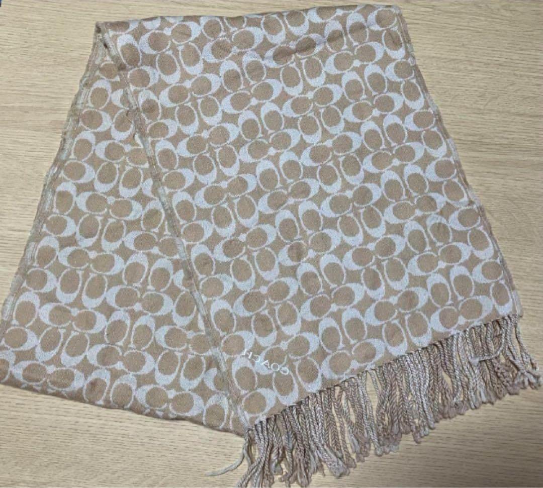 Beige and white COACH reversible scarf with signature 'C' pattern and fringe laid flat.