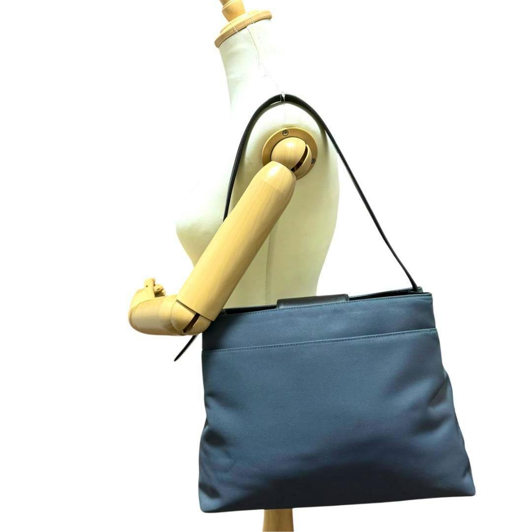 Gray canvas Coach shoulder bag displayed on a dress form mannequin with a single shoulder strap.