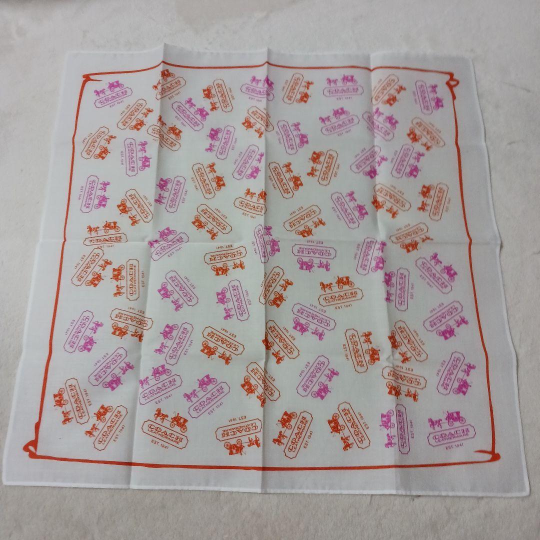 White polyester Coach handkerchief laid flat, printed with orange and pink Coach logo motifs.