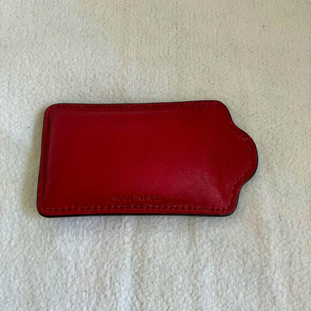 Red leather Coach paper weight photographed on a light fabric background.