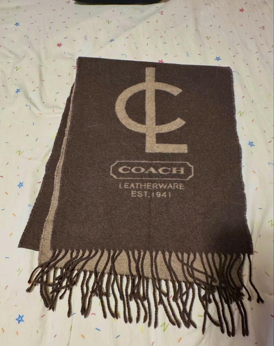 Brown COACH logo scarf with fringed ends laid flat showing the large logo and "LEATHERWARE EST. 1941" text.