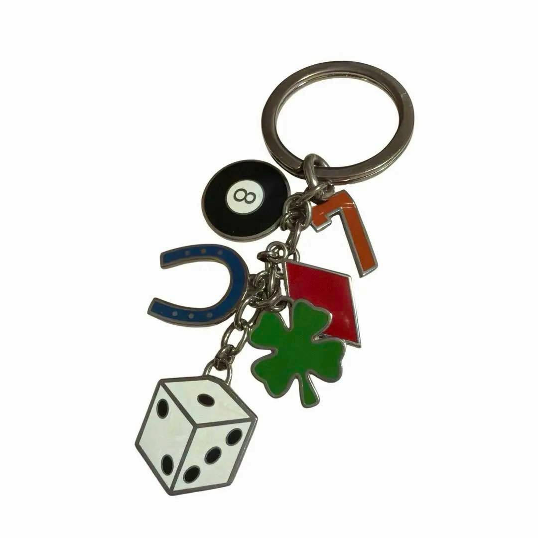 COACH keychain charm with multiple lucky motifs including an eight-ball, blue horseshoe, orange number 7, red house, green four-leaf clover, and a white die on a silver key ring.