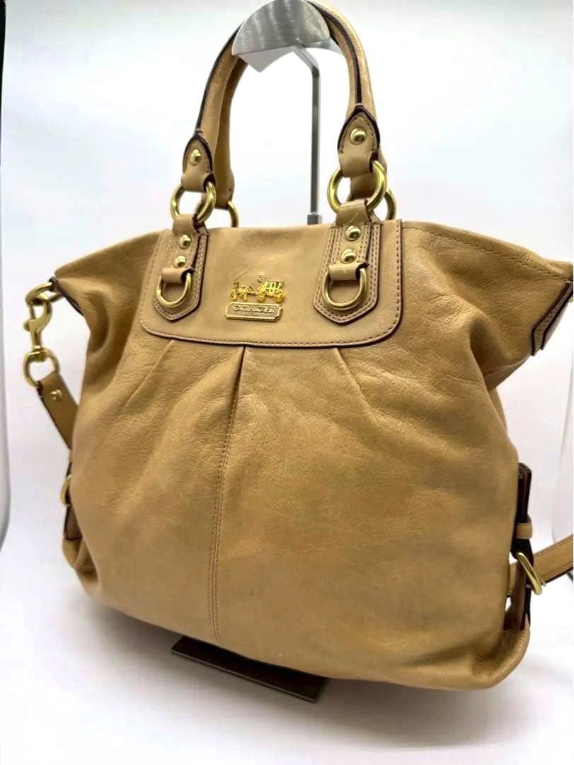 Front view of the COACH Madison 2WAY cow leather shoulder bag with gold hardware on a display stand.