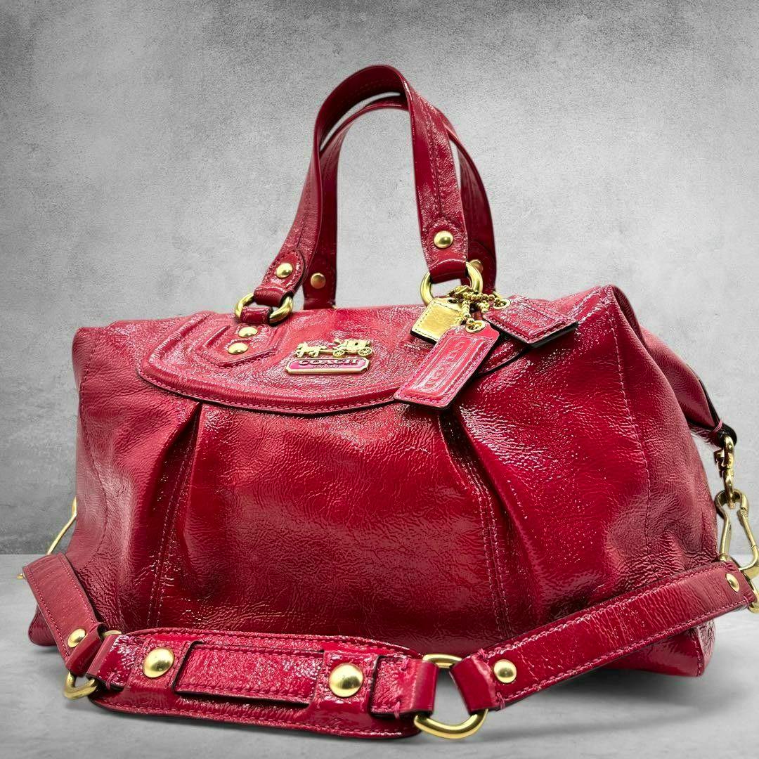Pink patent leather COACH Madison mini Boston 2way bag shown from the front on a grey textured background.