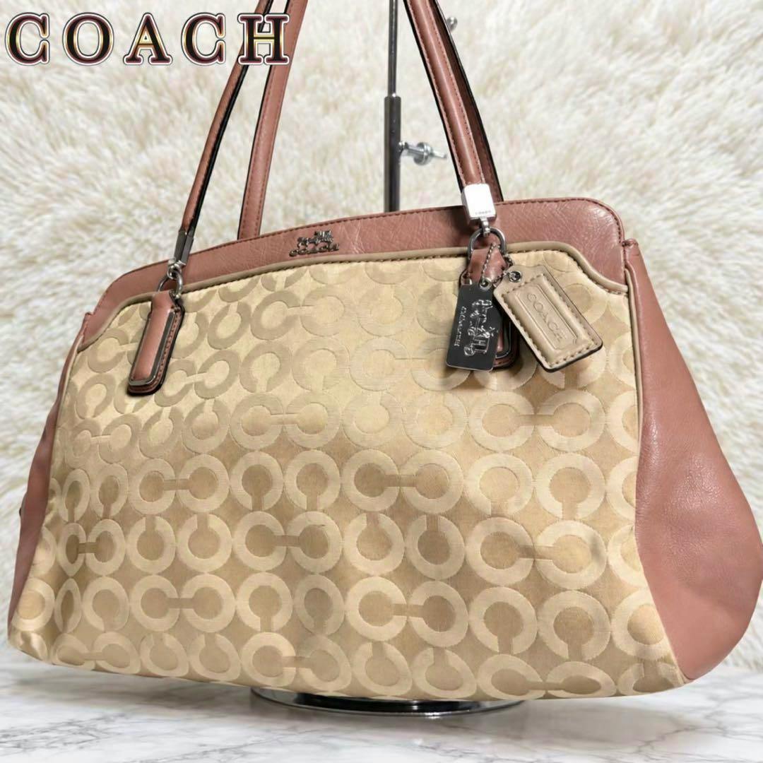 Coach Madison Op Art tote bag in beige op-art fabric with tan leather trim and Coach hang tags displayed on a light background.