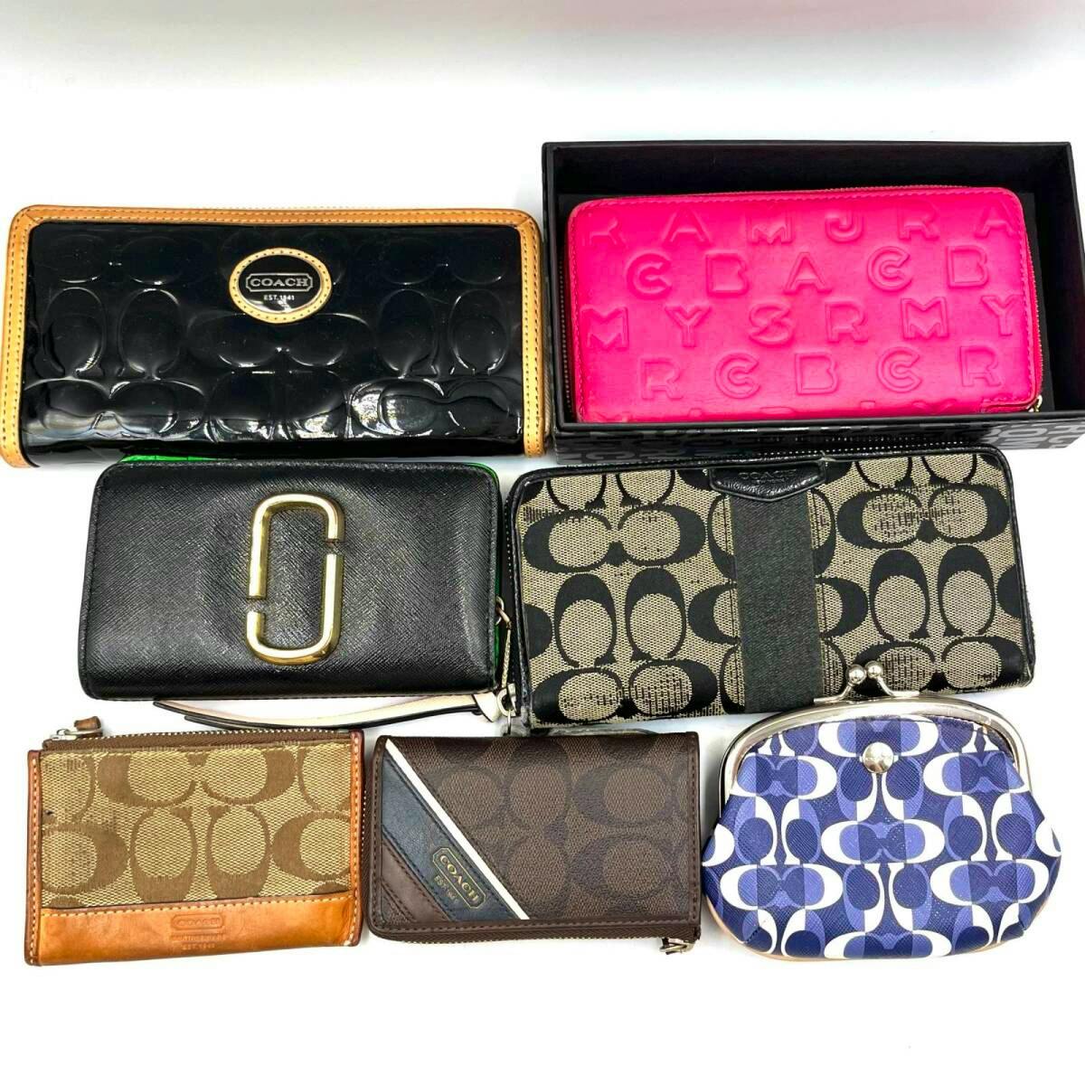 Seven wallets (Coach and Marc Jacobs) of various styles and colors arranged on a white background.
