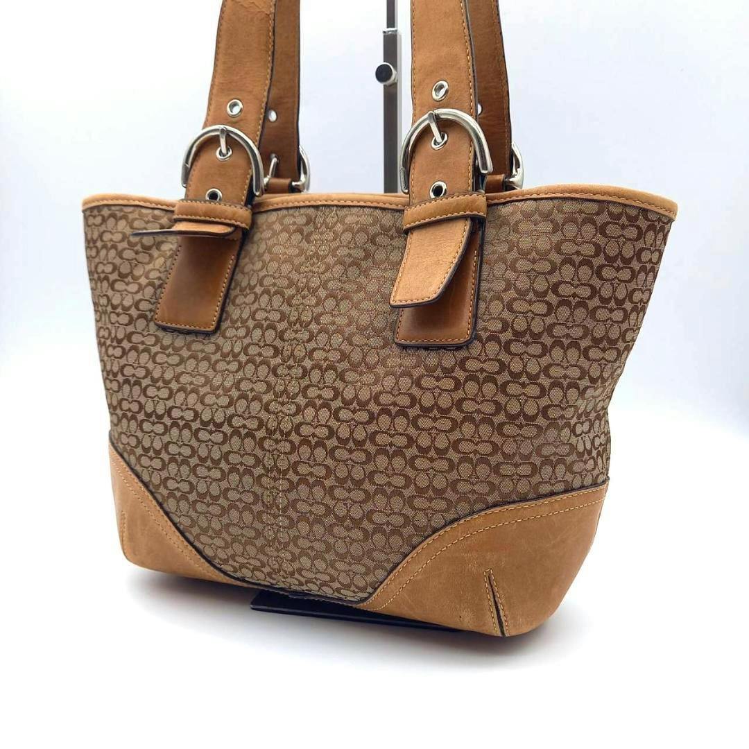 Front-left view of a brown COACH mini signature canvas tote bag with leather trim and shoulder straps.
