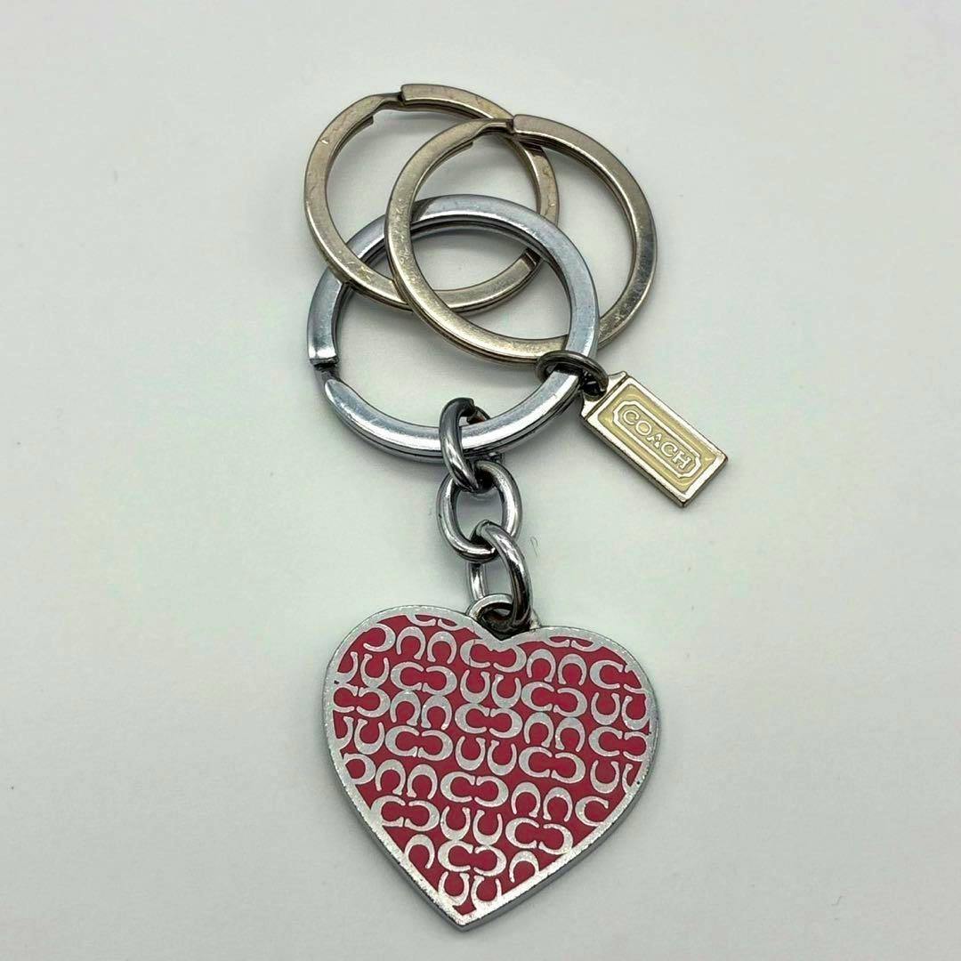 Pink heart COACH signature charm keychain with metal rings and a small rectangular COACH tag on a white background.