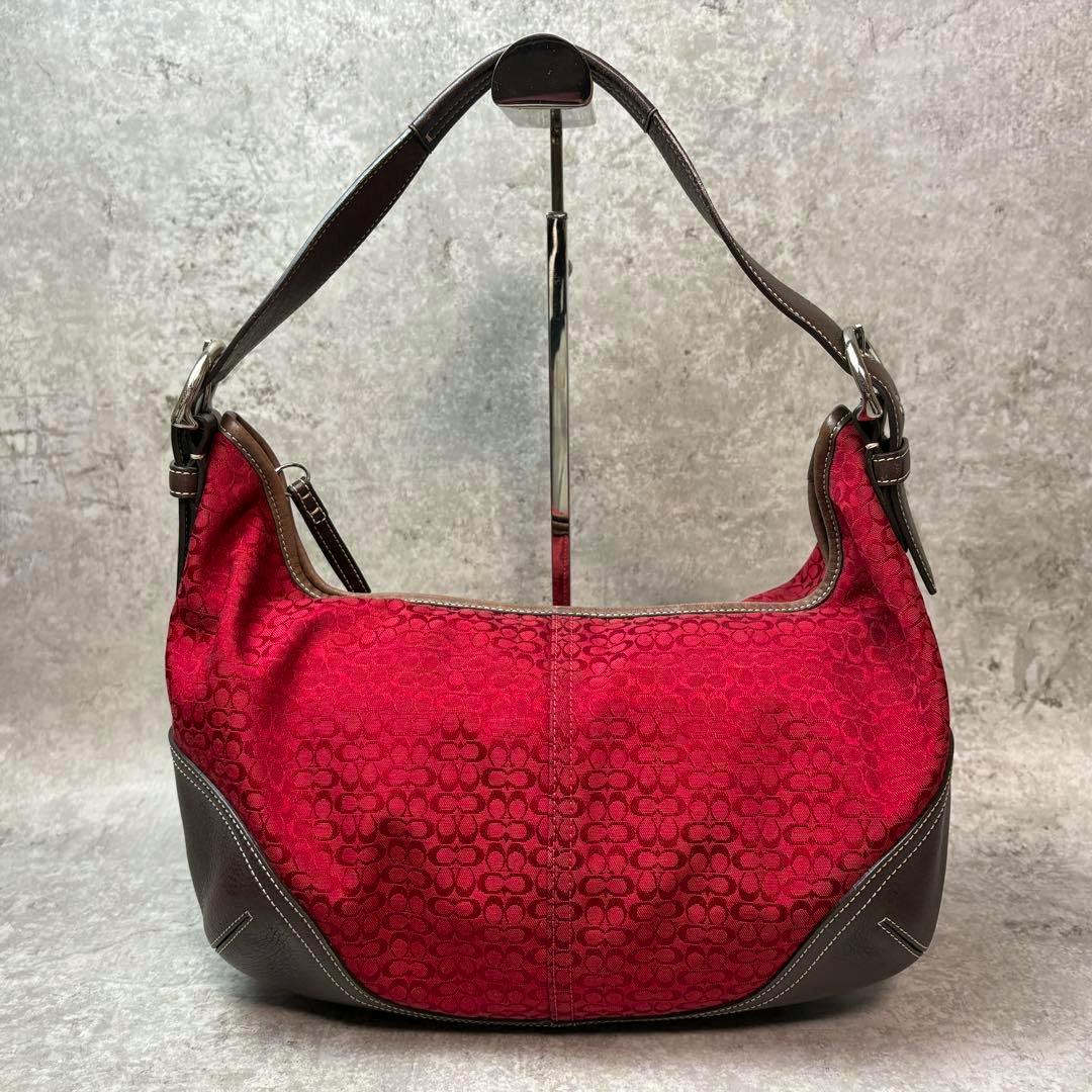 Red Coach mini hobo bag in signature canvas with brown leather trim shown on a display stand.