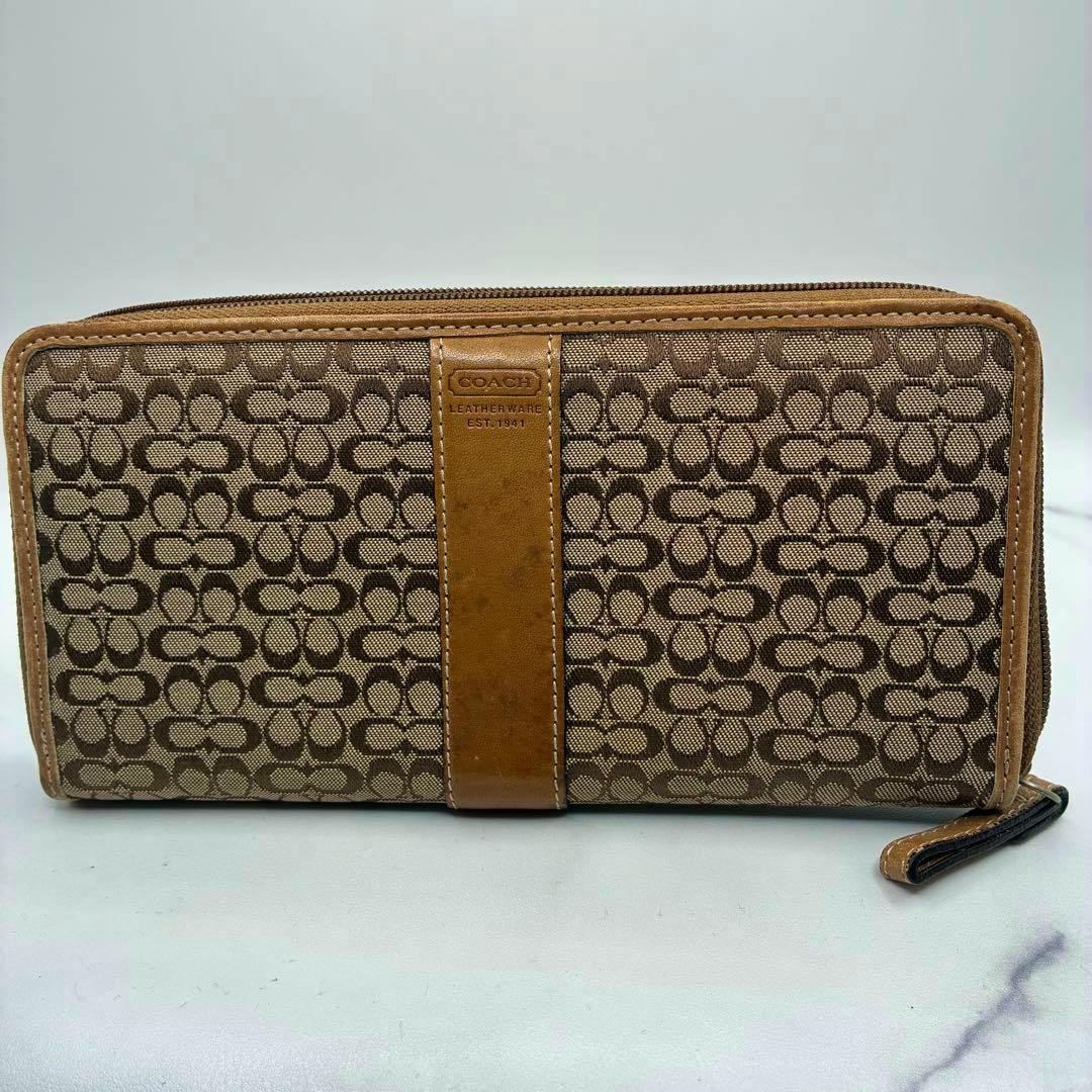 Brown Coach long zip-around wallet in mini signature canvas with a leather center strip shown from the front.