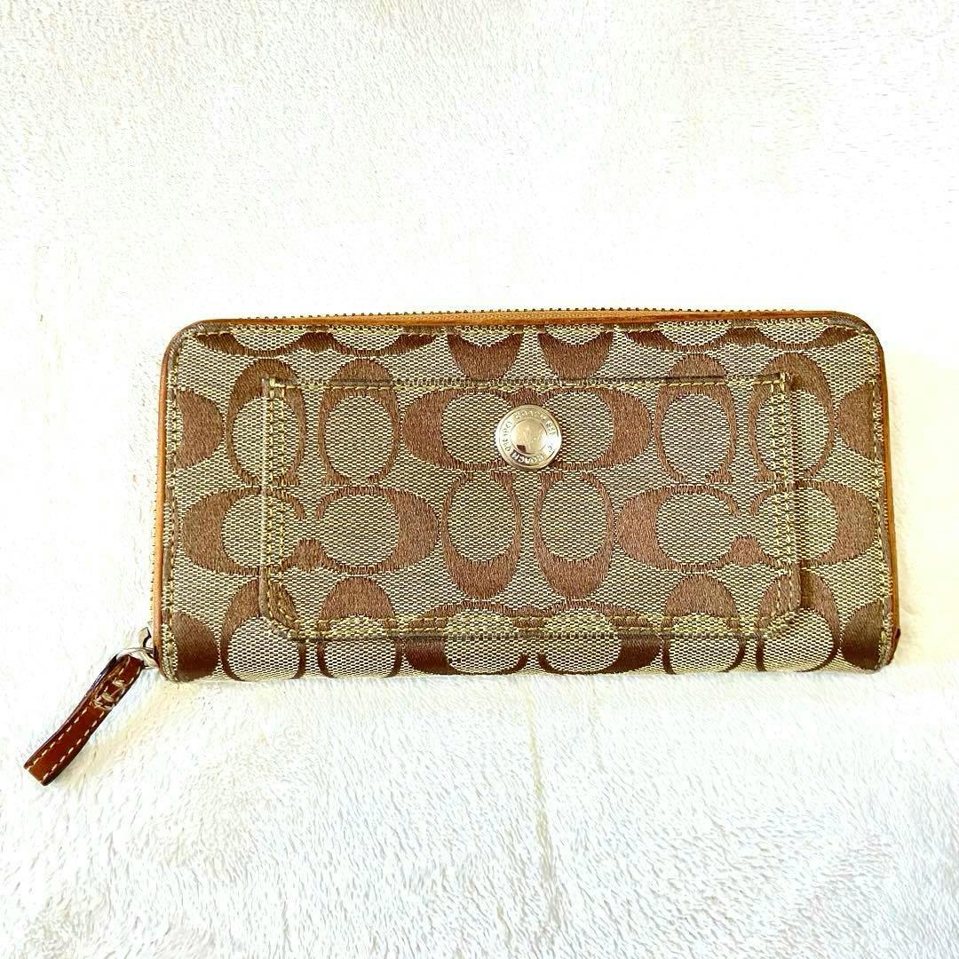 A Coach monogram-pattern long canvas wallet with a zipper pull laid flat on a white background.