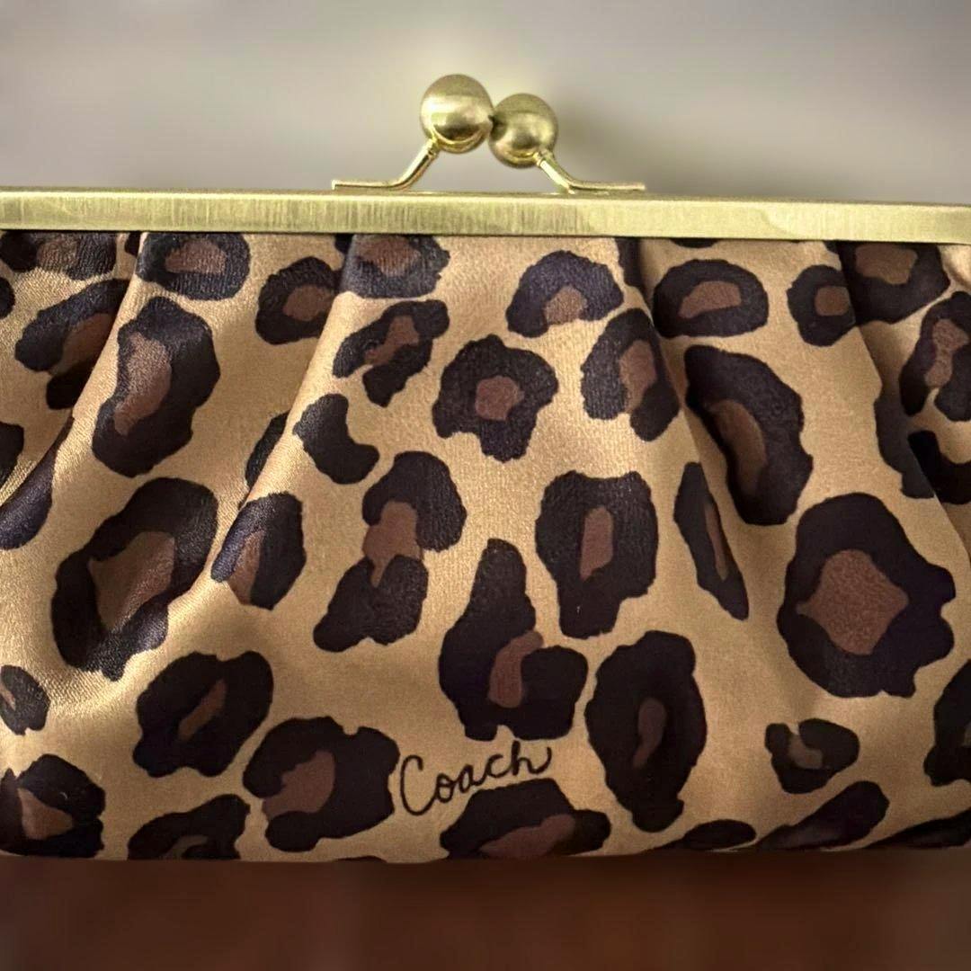Leopard-print Coach clasp pouch exterior with gold-tone kiss-lock frame and visible Coach logo.