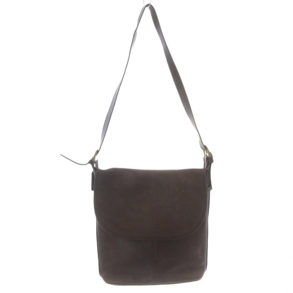 Brown leather COACH flap shoulder crossbody bag with long strap hanging against a white background.
