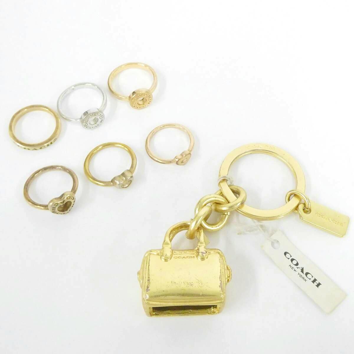 Gold-tone COACH bag-shaped keychain with multiple small metal rings and a COACH tag on a white background.